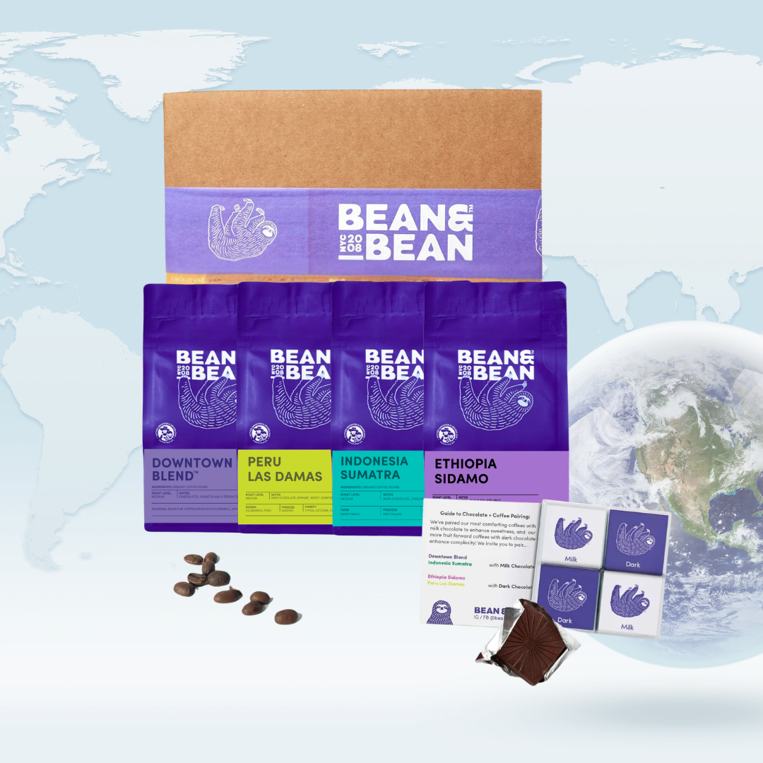A Bean & Bean gift set featuring a branded shipping box, four purple bags of coffee with different labels, a coffee-and-chocolate pairing card, and assorted chocolate squares, shown on a light world map background with a small globe in the corner.
