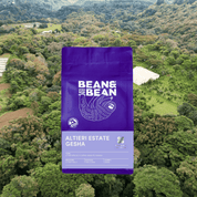 Purple Bean & Bean coffee bag labeled "Altieri Estate Gesha" set against an aerial view of a lush green farm.